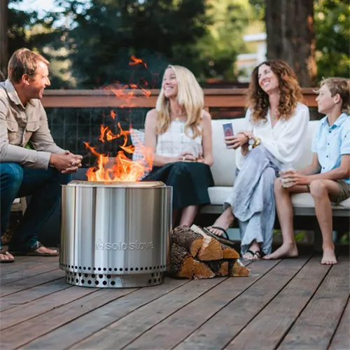 Menschen sitzen an einer modernen Feuerschale auf der Terrasse im Garten
