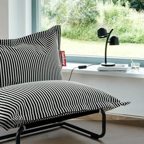 Fatboy table lamp next to a black and white striped bean bag in a modern living room